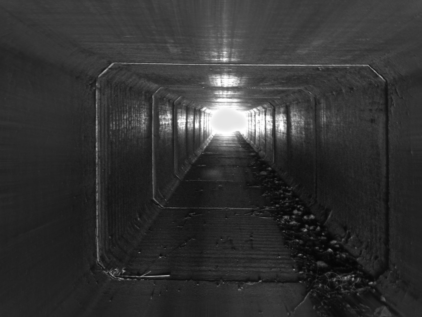 Black and white image of light at end of a long, dark tunnel 