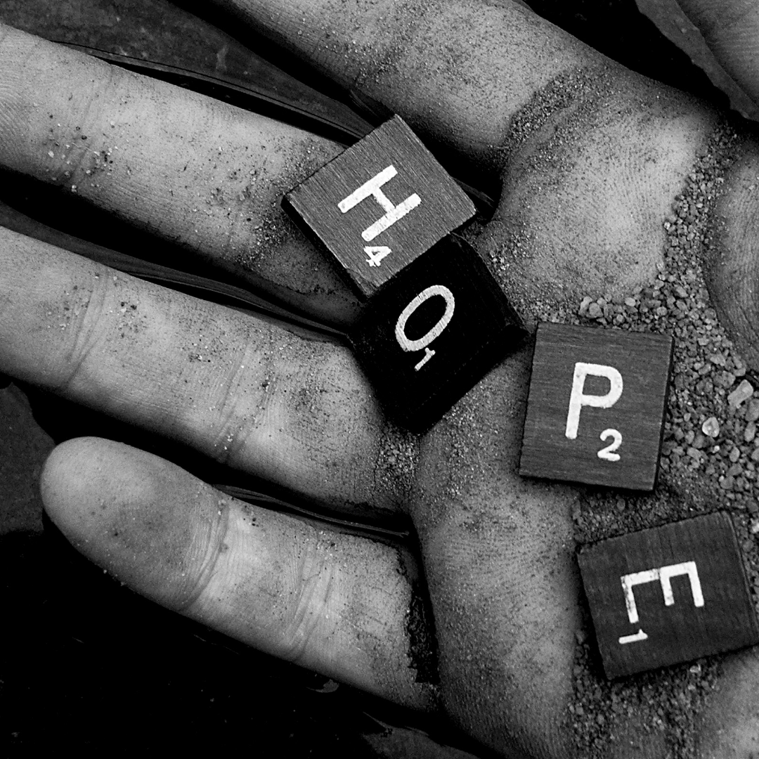 Hope spelled out by scrabble times on a hand covered in dirt 